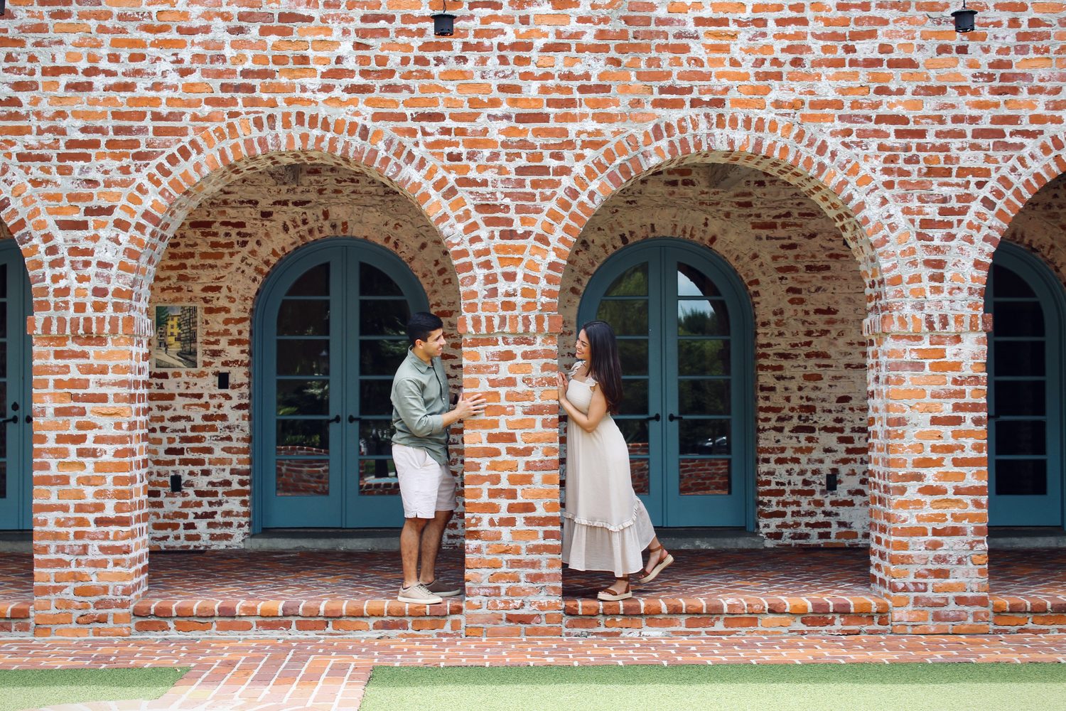 Couple standing in a brick archway with teal doors