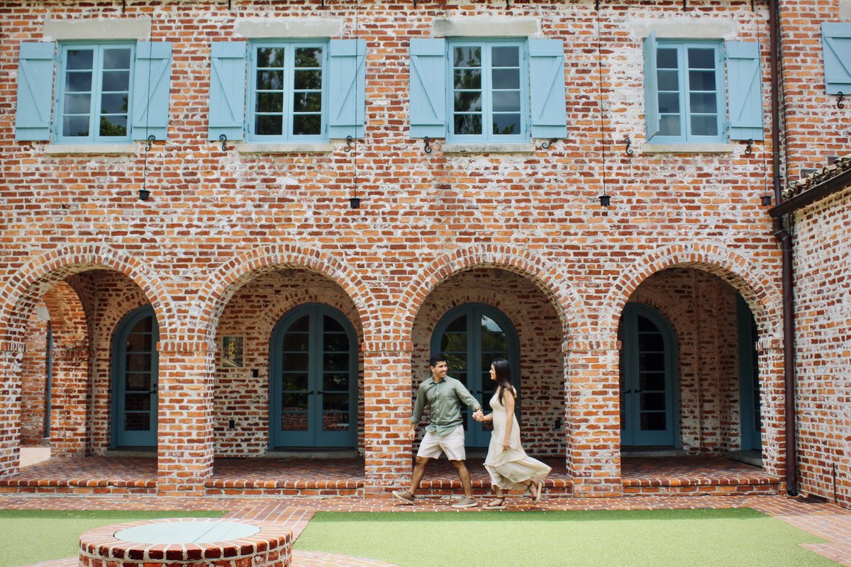 Couple walking together under brick archways with teal doors