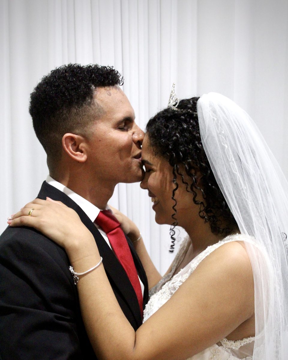 Bride and groom touching foreheads in a close embrace, her veil falling behind her