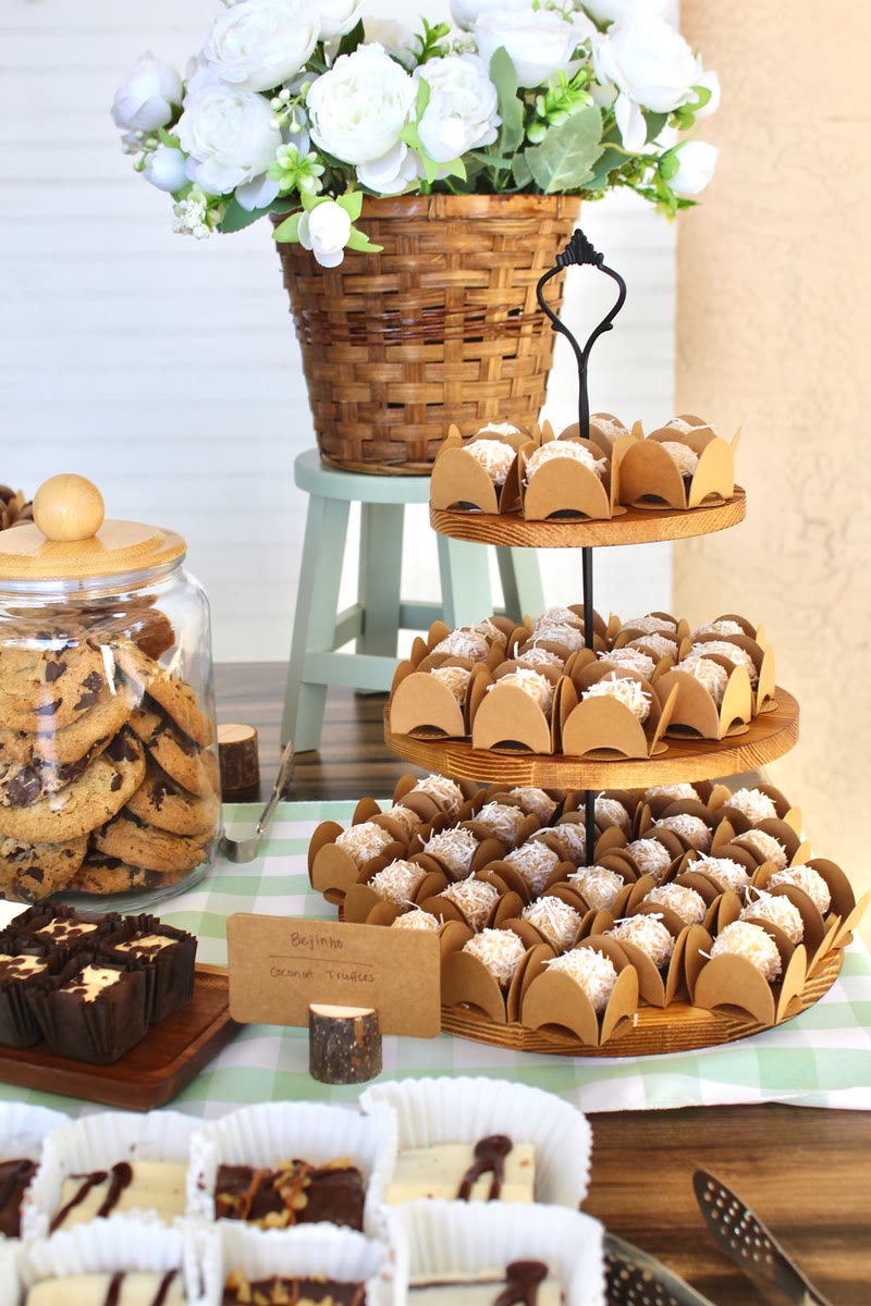 Dessert table with tiered trays of treats and a basket of white flowers