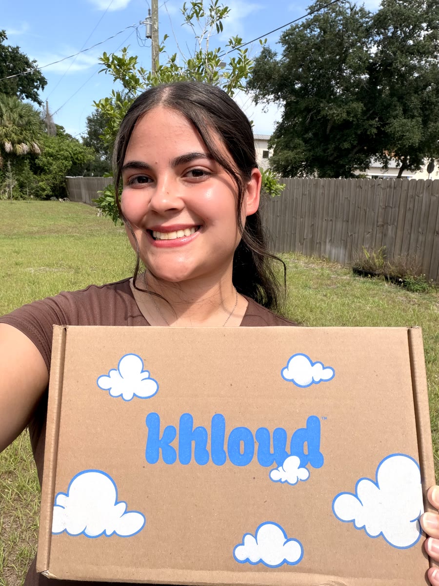 Kathlyn smiling outdoors and holding up a khloud box with blue cloud designs