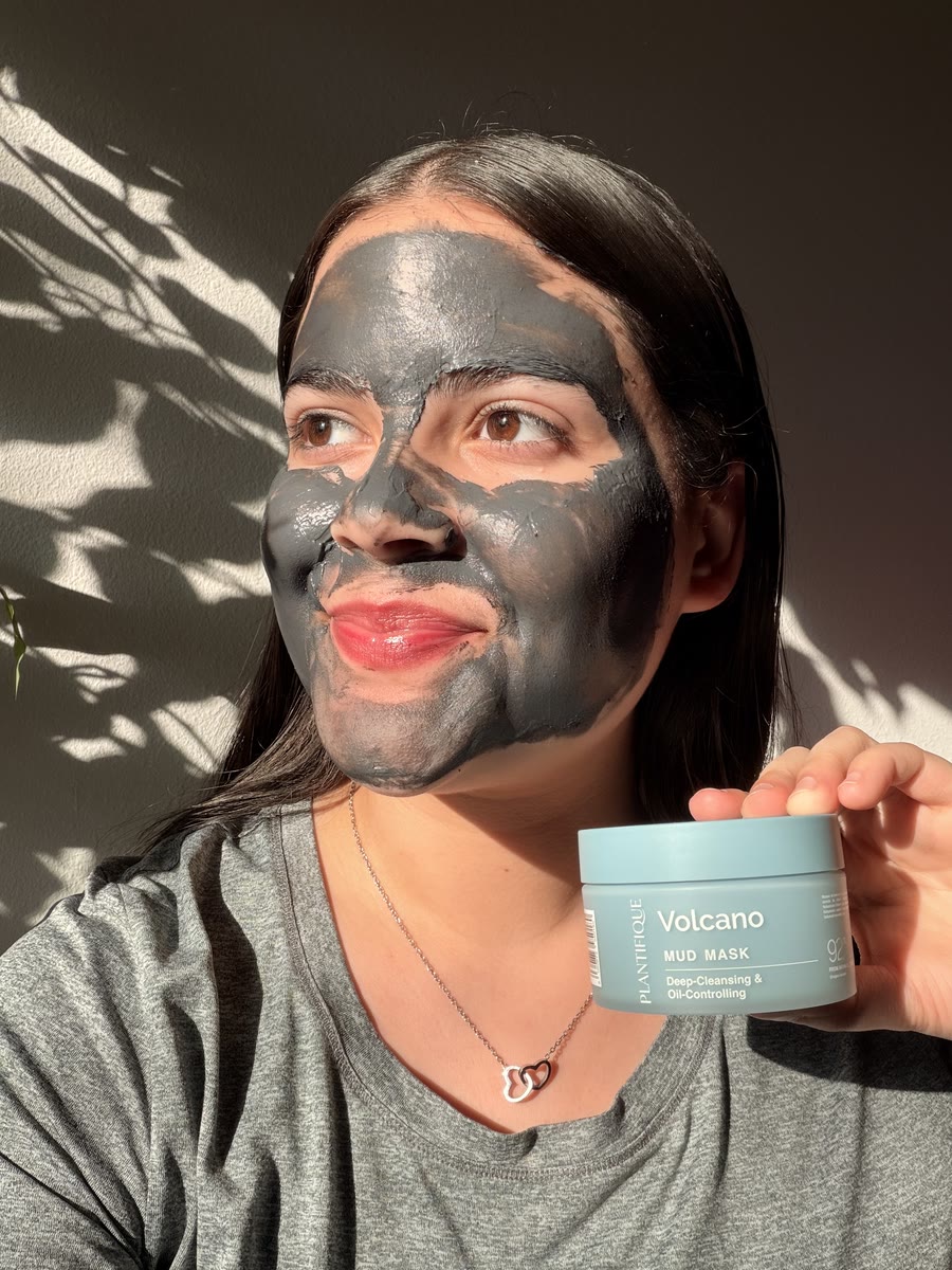 Kathlyn in a Plantifique Volcano mud mask, holding the jar and looking off to the side in the sunlight