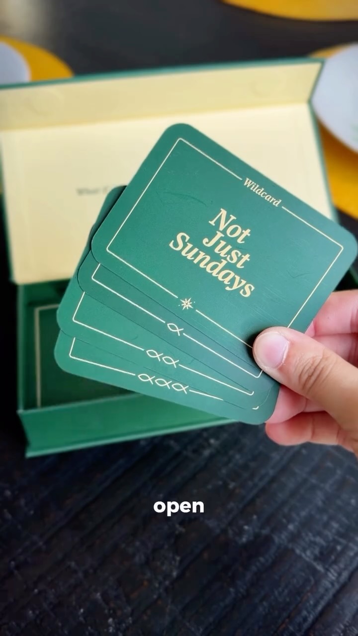 A hand fanning out green Not Just Sundays cards